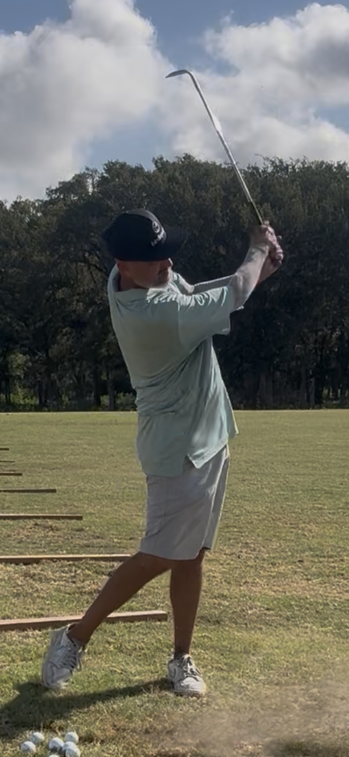 Simon Fagan finishing an iron shot on the practice range